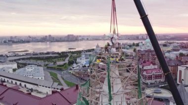 ALMATY, KAZAKHSTAN - 13 Ağustos 2023: Profesyonel işçi takımı kulenin tepesine beton yıldız yerleştirdi. Güvenlik için kask takan adamlar dekorasyon için ayakta duruyorlar.