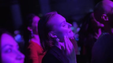 ALMATY, KAZAKHSTAN - 30 NOVEMBER 2023: Seçkin bayan hayran, en sevdiği grubun konserinde seyirci kalabalığında dans ediyor. Sarışın kadın en sevdiği müziği dinleyen bir sanatçıyla şarkı söylüyor.