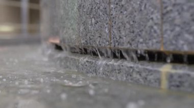 Temiz su fıskiyeleri granit duvardan havuza akıyor. Hızlı saydam jetler ve parktaki dekoratif çağlayanlar.
