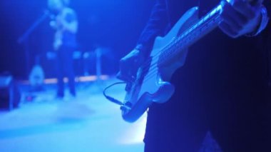 Müzisyen yakın çekimde grupla bas gitar çalar. Yetenekli gitarist, kulüpte dinleyicileri eğlendiren melodik sesler çıkarıyor.