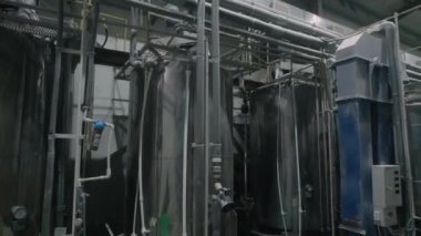 High stainless tanks with pipes for distillation processes in chemical plant workshop. Cisterns and pipeline system at plastic materials factory