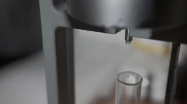 Clear drop falls down into test tube during oil fractional distillation in lab closeup. Chemical processing of extracted materials
