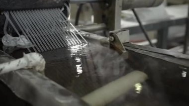 Cooling down hot plastic threads with water in recycling workshop closeup. Technology of waste materials reusing at chemical factory
