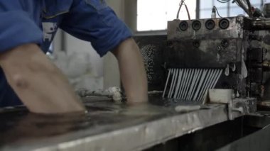 Worker pulls plastic threads through water reservoir to cool down in workshop closeup. Employee works with synthetic materials at plant
