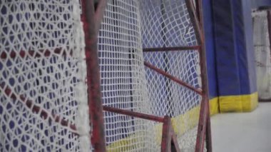 Hockey puck goes into gate on ice arena closeup. Hockey practice on professional ice arena with specialized equipment before competition