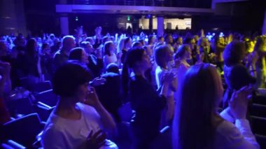 ALMATY, KAZAKHSTAN - NOVEMBER 28 2023: Crowd of fans applaud after listening to music of favorite band in concert hall. Joyful audience celebrates band standing up in appreciation