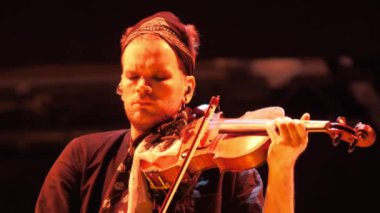 ALMATY, KAZAKHSTAN - 28 Kasım 2023: Erkek kemancı düşük ışık yakın çekim altında sahnede duruyor. Müzisyen hayranları için çalan telli enstrümanla zarif sesler çıkarıyor