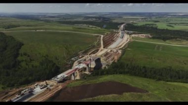 Resimli yaz kırsalında köprüsü olan bir otoyol inşaatı. Trafik köprüsü içi boş hava panoramasında vinçlerle birleştirildi