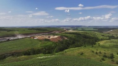 Yeşil Vadi 'deki yol inşaatı alanının yanındaki çıkış çukuru. Yaz kırsal manzarasında yol bakımı için inşaat malzemeleri.