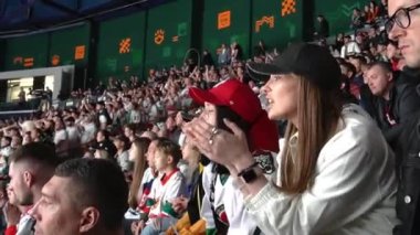 ALMATY, KAZAKHSTAN - 22 Aralık 2023: Hevesli bayan hayran hokey maçı sırasında tribünlerde otururken arkadaşlarıyla tartışır. İzleyiciler ulusal hokey şampiyonasını yakından izliyor