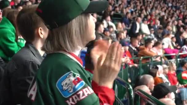 アルマニー カザフスタン December 222023 女性ファンは 手を叫び 拍手することでホッケーチームをサポートしています お気に入りのチームのロゴに寄付された若い女性は ファンの群衆の間でスタジアムトリビューンに座っています — ストック動画