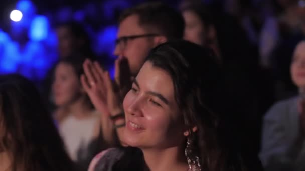 アルマニー カザフスタン ナチュラル 2024 若い女性はファンの群衆を応援するために立って大好きなヒットに沿って歌います 人々はコンサートホールでミュージシャンを支援するユニゾンで手を握ります — ストック動画