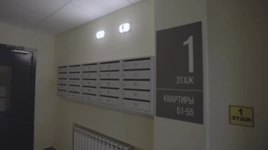 Posta kutuları ve duvarında açık navigasyon işareti olan bir apartmanın geniş giriş salonu. Hızlı gezinme için daire numaraları içeren zemin