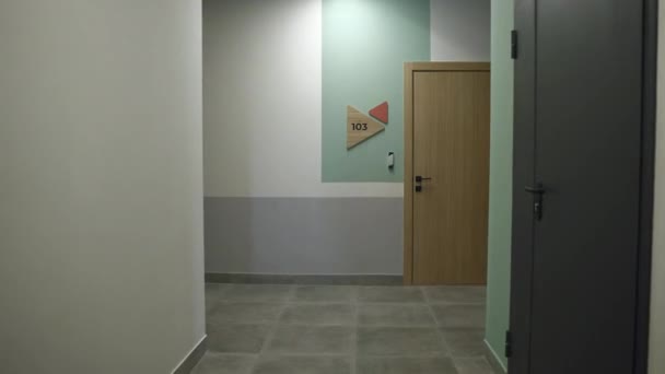 アパート番号付きのスタイリッシュな木製ボードは ドアの近くの壁に掛かります ミニマルなデザインの高層ビルのモダンなエントランスホール — ストック動画