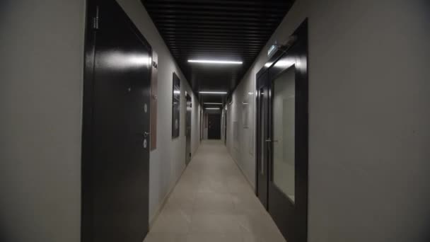 廊下は両側にオフィスドアが並んでいる Ledランプの照明に浴びたホールは ビジネスセンターのインテリアデザインを示しています — ストック動画