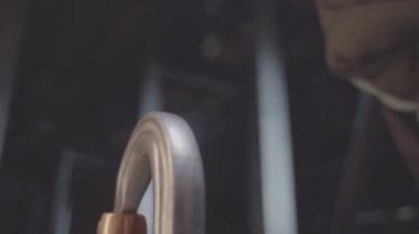 İşçiler yarı karanlık odada yay çıtçıtçıtını metal döngüye bağlıyor. İnşaatçı fabrika atölyesinde çalışmak için güvenlik ekipmanı hazırlıyor