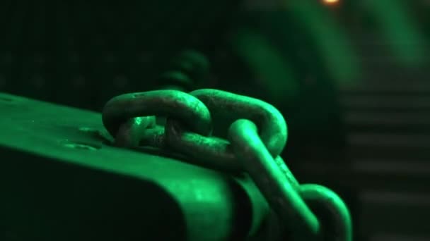金属部分の穴を通って引っ張られた鉄の細胞が付いている鎖は緑色のライト クローズアップを締めました 倉庫の重い貨物持ち上がるメカニズム要素 — ストック動画