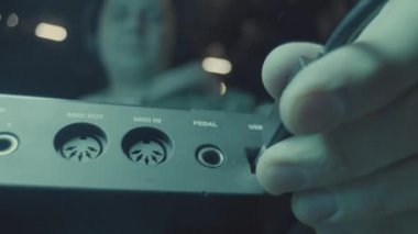 Müzisyen, karanlık ses stüdyosundaki müzik sentezleyicisinden kablo çekiyor. Konser sahnesinde ses ekipmanı. Dijital aygıt