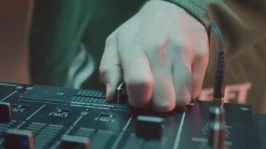 DJ gece kulübünde müzik çalarken konsolda hızlı ilerliyor. Adam çılgın dans partisinde ses mikserinde çalışıyor. Çağdaş eşitleyici