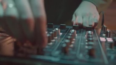 DJ, gece kulübü partisinde konsolun düğmelerini açıp müzik çalıyor. İnsan elleri ses mikserinde ses modunu kullanır. Dans seti