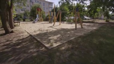 Boş çocuk parkı yerleşim yerinin kalbinde duruyor. Renkli salıncaklar ve kaydırak apartmanlı avluda