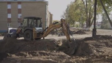 ALMATY, KAZAKHSTAN - 23 AĞUSTOS 2024: deneyimli operatör verimli kazıyı sağlamak için kova ayarlar. Profesyonel çalışan, iş sırasında deliğin derinliğini ve genişliğini izler