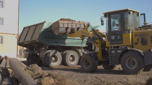 アルマニー カザフスタン 2024年 プロのドライバーがフロントローダーを巧みに操作します 現代的なフロントローダー掘削機は待機トラックにバケツと土を降ろします — ストック動画