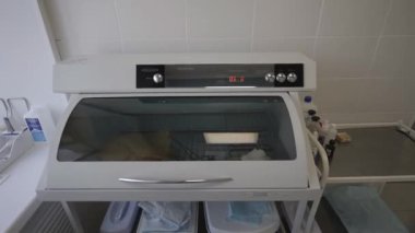 Kuvars sterilizatörünün içinde tıbbi aletler var. Hastane çalışanı sterilizasyon odasında ameliyattan önce tıbbi aletleri sterilize ediyor.