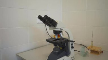 Hastane laboratuarındaki masaya yerleştirilmiş elektronik mikroskop. Kan tahlillerini detaylı incelemek için son teknoloji profesyonel bir cihaz.