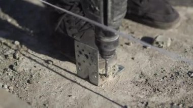 İşçi, pervane ve koç sürgüsü kullanarak beton kirişe açı ışını yapıştırıyor. Açık hava atölyesinde inşaat prosedürü canlandırıcı.