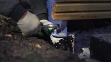 İnşaatçı ingiliz anahtarı kullanarak beton-plastik yapıya sıkıca tutunuyor. İşçi bahçe tezgahı yapmak için parçaları topluyor
