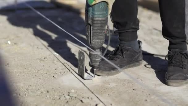 Werknemer Bevestigt Hoekbalk Aan Betonnen Vloer Met Behulp Van Perforatiemachine — Stockvideo
