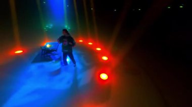 DJ, canlı ışıklarla aydınlatılmış sahnenin merkezinde duruyor. Sahne aydınlatmasının ihtişamıyla çevrili müzik konsolu karıştırıyor