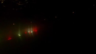 Sahnenin karanlığında beyaz ve kırmızı ışık huzmeleri parıldıyor. Işıkların etkileşimi performans sırasında ritim ve hareket hissi yaratır