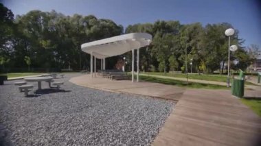 Şehir parkının kalbinde dinlenmek için masaları olan modern bir çardak. Konforlu dinlenme alanı yaz pikniklerinin tadını çıkarmak için mükemmel bir seçenek sunar
