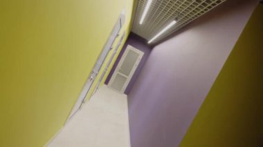 Dar koridorlarda parlak boyanmış duvarları olan sınıflara açılan plastik kapılar. Çocuk ilkokulunda modern yenileme
