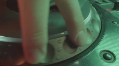 Deneyimli DJ koşu tekerleğini kumanda üzerinde kullanarak rayların temposunu ayarlar. Profesyonel müzisyen koşu çarkını döndürüyor şarkının ritmini hızlandırıyor