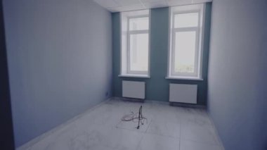 Küçük sınıf, yumuşak pastel gölgelerle süslenmiş duvarları gösteren boş duruyor. Gün ışığı pencerelerden içeri giriyor, odayı sıcaklıkla dolduruyor.