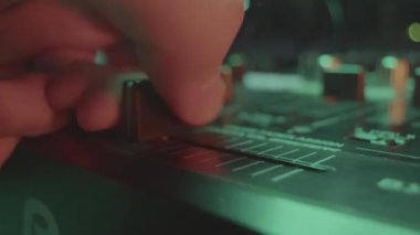 DJ ses karıştırıcı konsolunu hassasiyet ve uzmanlıkla çalıştırıyor. Becerikli müzisyen ses kalitesini sağlamak için kaydıracı manipüle eder