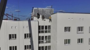 ALMATY, KAZAKHSTAN - 07 Mart 2024: Çok katlı binaların duvarlarını tamamen kapsayan boya ile kaplayan yapıcılar. Ressamlar profesyonelce bitirmek için özenle çalışırlar.