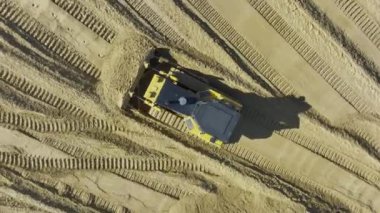 Modern buldozer, pürüzsüz yüzeyi hazırlayan kum yığınını hareket ettirir. Profesyonel ekipman, malzeme kullanımının devamı için çamur kurutma yataklarını temizliyor