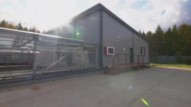 Parlak güneş ışığı ağır çekimde, duvarları açık olan hava atölyesi. Kırsal kesimdeki kanalizasyon su arıtma tesisi. Geri dönüşüm teknolojisi