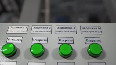 Fabrika atölyesinde yeşil plastik düğmeli ve etiketli kontrol paneli. Rezervuar mandalları elektrik teçhizatı ile açılıyor
