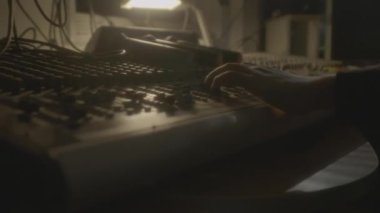 Kişi kolu yarı karanlık stüdyoda DJ konsoluna ayarlar. Müzisyen, gece kulübündeki kontrol panelinde şarkıları karıştırıyor. Ses ekipmanları