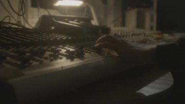 DJ el, yarı karanlık kabinde konsolun kollarını hareket ettiriyor. Müzisyen, gece kulübünde dijital ekipmanlarla dans eder. Ses stüdyosu
