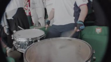 ALMATY, KAZAKHSTAN - 28 Haziran 2024: Hokey takımı taraftarı yakın çekimde davul çalıyor. Yaratıcı taraftarlar modern stadyumdaki müzik performansıyla yerel oyuncuları alkışlıyorlar.