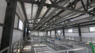 Pencereli iyi aydınlatılmış atölye, beton bölümlere bölünmüş sıvı tanklar. Atık suyu tortullamak için havzalar. İçerideki fabrika işlemlerine bak