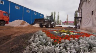 Kazıcı, atölye binasının önünden geçen fabrika arazisinden geçiyor. Şehrin sanayi bölgesinde inşaat. Makine kullanılarak boru hattının döşenmesi