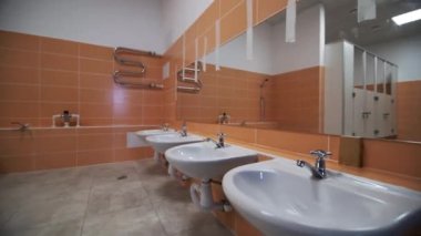 Geniş banyo özellikleri krom musluklarla donatılmış lavabolar. Duvara monte edilmiş büyük ayna modern banyo tasarımının ayrıntılarını yansıtır.