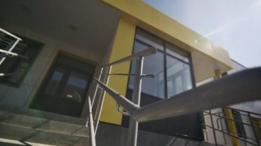 Paslanmaz çelik parmaklıklı merdiven gün ışığında parlıyor. Merdivenlerin kenarlarına monte edilmiş demiryolu modern mimariyi tamamlıyor.